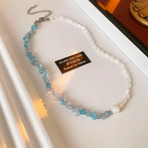 Detailed close-up of 925 silver necklace with blue crystal stones and white shell pearls