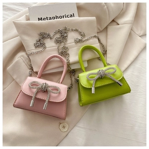 Detail of trendy mini crossbody bag with crystal bow buckle and silver metal chain strap