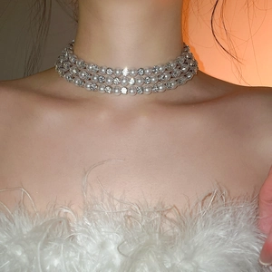 Close-up of triple-layer pearl and rhinestone bow necklace set on a model's neck