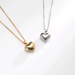 Macro detail of gold and silver heart pendants with ribbed texture on sleek metal chains