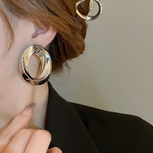 Close-up of a large silver oval hollow earring on a model in a black suit jacket
