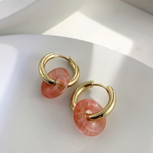 Macro detail of 18K gold stainless steel hoop earrings with natural marble stone texture
