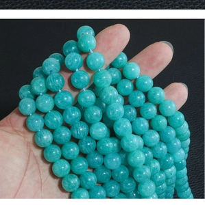 Macro detail of natural amazonite round beads with unique stone textures held by hand