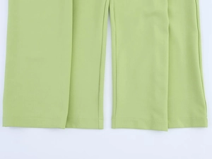 Gros plan sur le tissu tissé vert clair et l'ourlet à double couture du pantalon