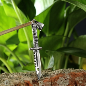 Macro view of silver stainless steel dagger pendant with textured handle on a rock