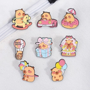 Detailed close-up of eight cute capybara enamel pins on white canvas fabric background