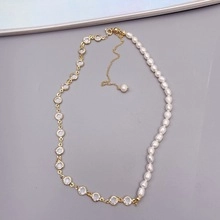 Detail of asymmetrical gold-plated necklace with white pearls and round clear crystals