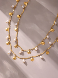 Close-up of golden shell pendants and baroque pearls on a stainless steel chain