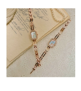 Detailed view of rose gold rectangular watches with diamond bezels on a vintage background