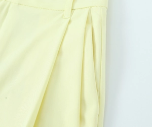 Detailed macro view of yellow twill fabric with waist pleats and precision stitching