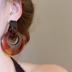 Close-up of vintage resin hoop earrings in amber tortoise shell color on model