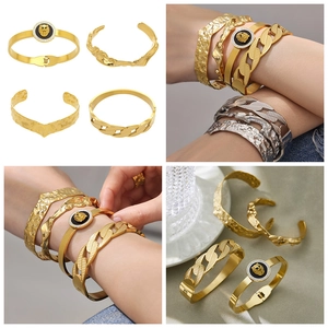 Macro detail of lion head medal and hammered gold bangles stacked for a heavy metal look