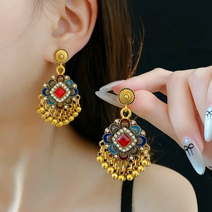 Détail de boucles d'oreilles vintage dorées avec pampilles et strass multicolores