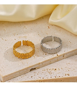 Detail of adjustable gold and silver textured bead rings on a textured stone surface