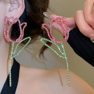 Detailed view of tulip tassel earrings with pink and green rhinestones worn by a model