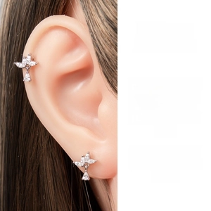 Close-up of sparkling zirconia flower studs in silver steel on earlobe and cartilage