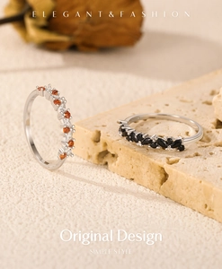 Elegant silver s925 rings with orange and black stones on stone display background