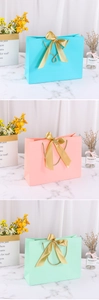 Vertical display of gift bags in blue, pink, and green with golden ribbon bows