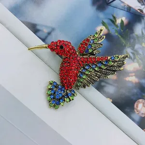 Detailed macro view of hummingbird brooch featuring vibrant red, blue, and green rhinestones