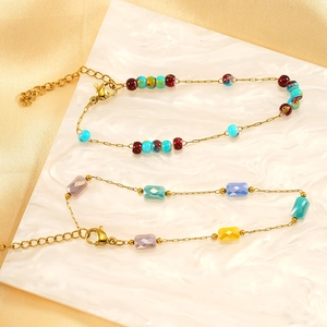 Bohemian gold chain bracelets with colorful crystal beads on elegant white textured surface