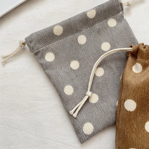 Macro detail of polka dot corduroy drawstring pouches with clear fabric texture and cotton ropes
