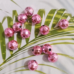 Macro shot of pink faceted faceted globe beads on a tropical leaf pattern background