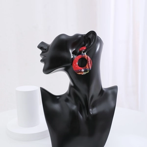 Detail of red tartan fabric hoop earrings displayed on a professional matte black stand