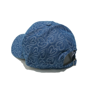 Detailed view of denim baseball cap with heart jacquard pattern and metal adjustment buckle