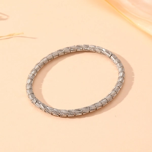 Detail view of silver twisted cable bracelet with elegant woven texture on a beige background