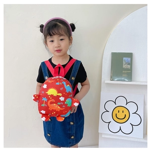 Close-up of cute red kids backpack with colorful dinosaur prints worn by a toddler