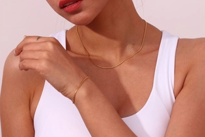 Detail view of a gold-plated S-chain necklace and bracelet set on a model