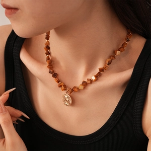 Macro shot of vintage shell bead necklace with a golden embossed portrait pendant on a model