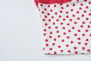 Gros plan d'un haut blanc avec motifs de cœurs rouges et bordure en dentelle