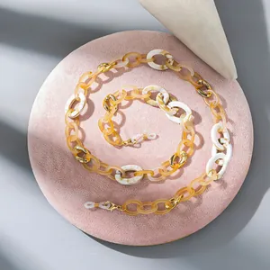 Detail of trendy acrylic eyewear chain with amber links and gold accents on pink velvet