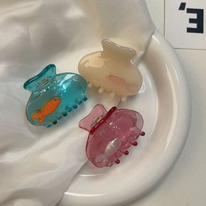 Detailed view of small fish claw clips in pastel blue, cream, and pink acrylic textures