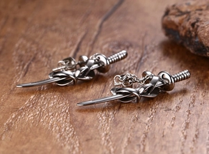 Macro shot of vintage silver sword-shaped stud earrings on a natural wood surface