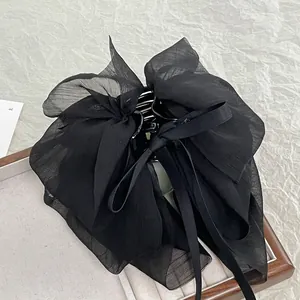 Elegant black chiffon bow hair claw clip made of double-layered sheer fabric on a tray