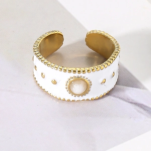 Detailed close-up of wide gold ring with white enamel, studs and white gemstone inlay