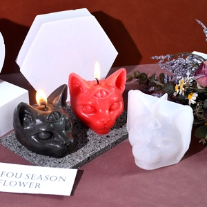 Detailed view of 3-eyed cat candle mold with black and red gothic scented candles