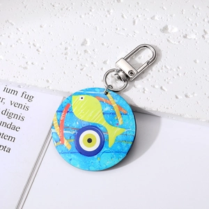 Bohemian tribal keychain with yellow fish and blue evil eye pendant on white surface