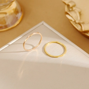 Close-up detail of two 1mm faceted stackable rings in yellow gold and rose gold
