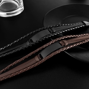 Close-up of layered braided leather bracelets in black and brown with a metal plate