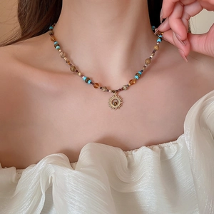 Close-up of beaded necklace with gold sun pendant and colorful natural stones on model
