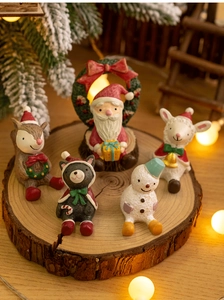 Detailed close-up of miniature resin Christmas figurines on a rustic wooden stand