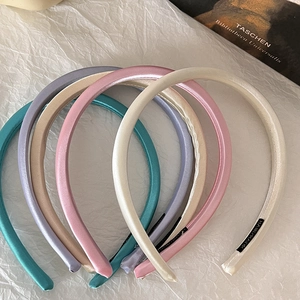 Macro shot of colorful satin padded headbands with handmade labels on white textured paper