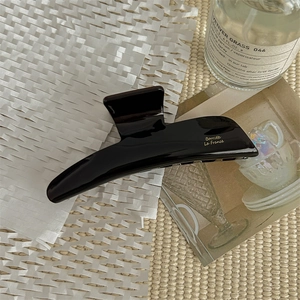 Detail of black acetate hair claw clip with golden Bonnette La France text engraving