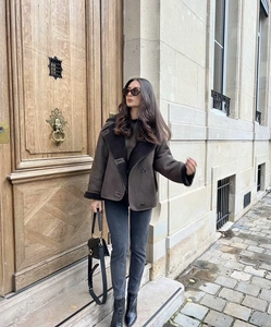 Deep brown shearling jacket with faux fur lapels styled with dark denim and boots