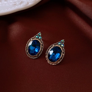 Détail de boucles d'oreilles vintage avec pierres bleues sur soie rouge de luxe