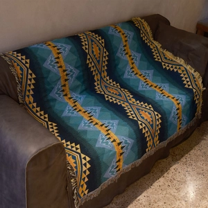 Close-up of bohemian knit blanket with geometric patterns and fringe edges on a sofa