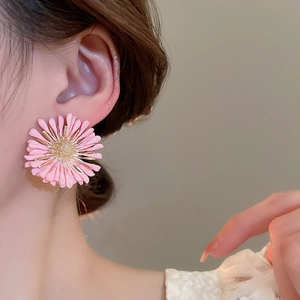 Close-up of pink raffia daisy earrings with golden stamen on female model